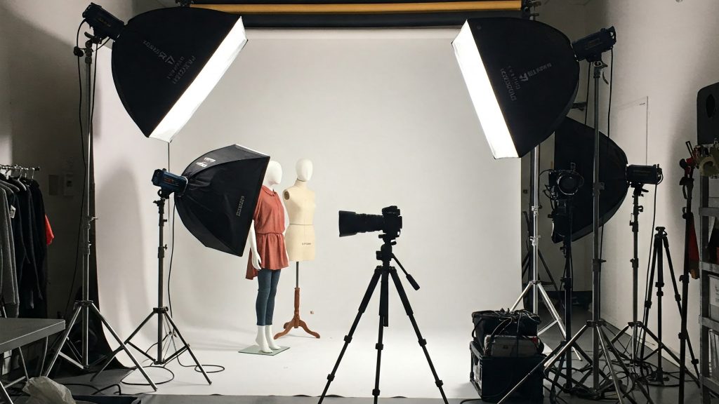 Photography studio setup for ghost mannequin shots with lights, camera, and mannequin